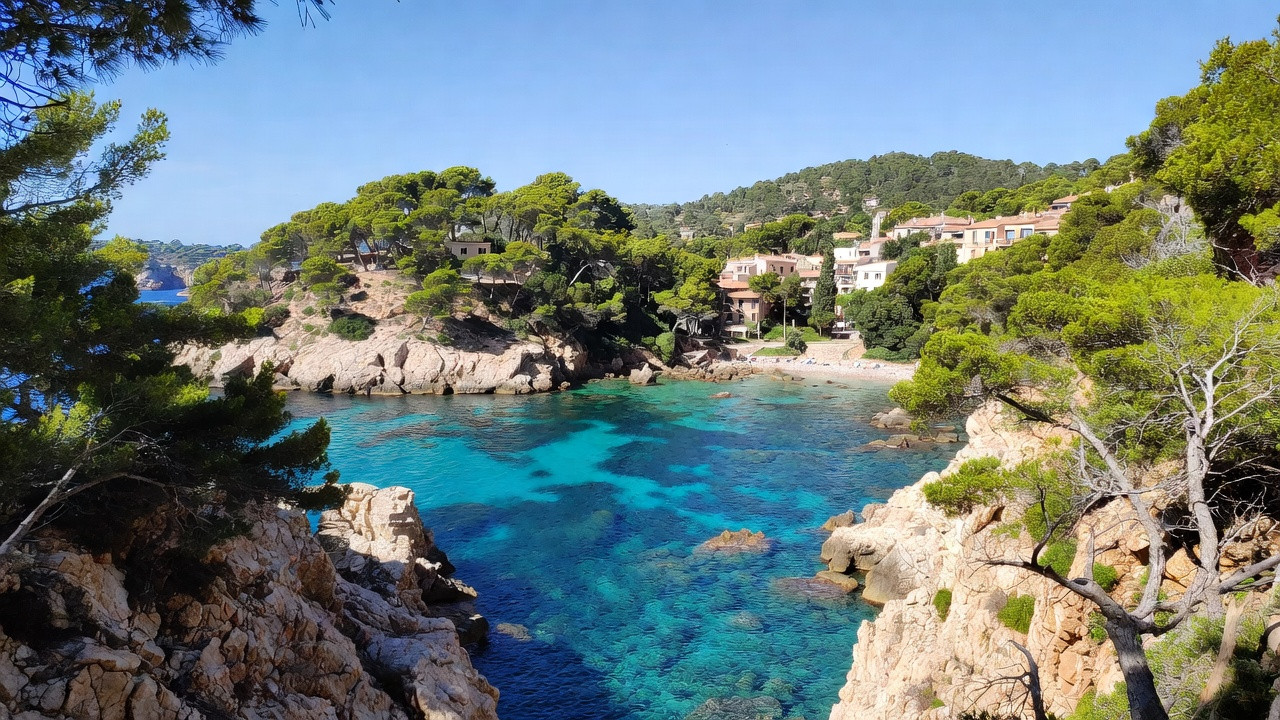 Crique de la Costa Brava aux eaux turquoise entourée de falaises et de pins, illustrant les meilleurs endroits à visiter